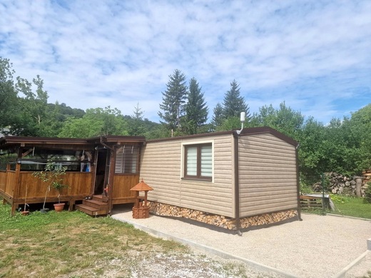 Mobilný dom s bezúdržbovým obkladom, krytou terasou a zásobou dreva v prírodnom prostredí